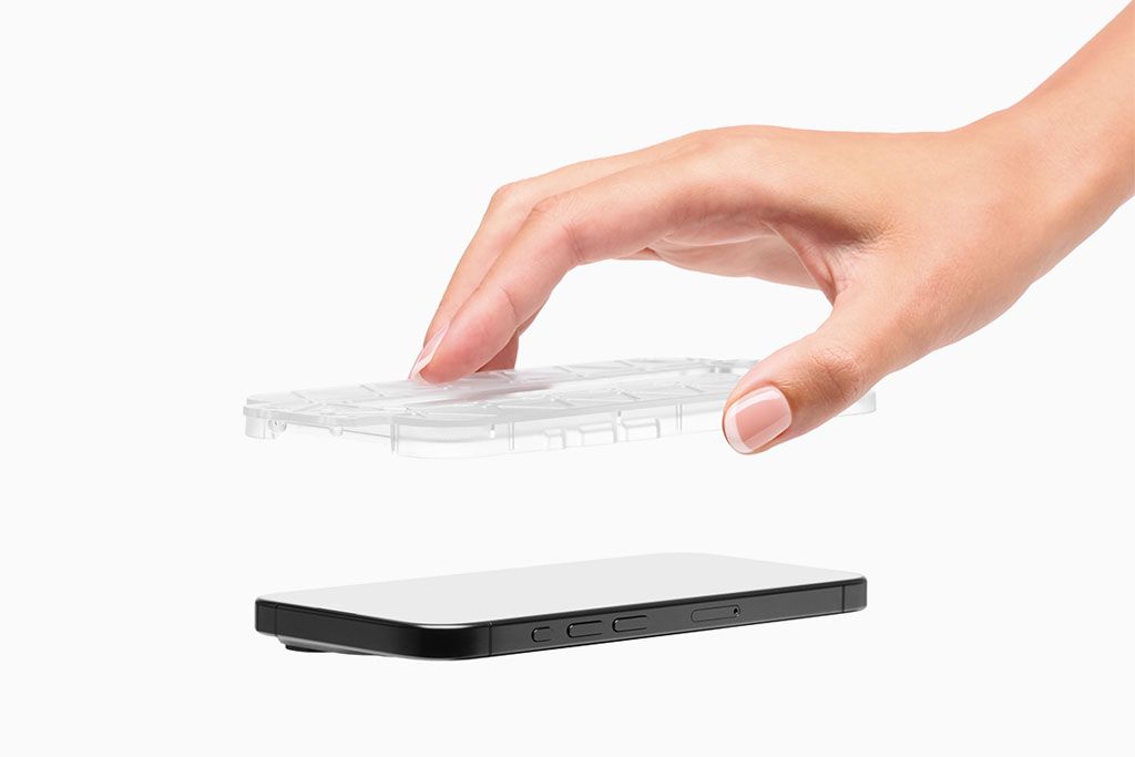 A hand holding a Prism 2.0 Installation Tray over an iPhone with the screen side up, moments before installation