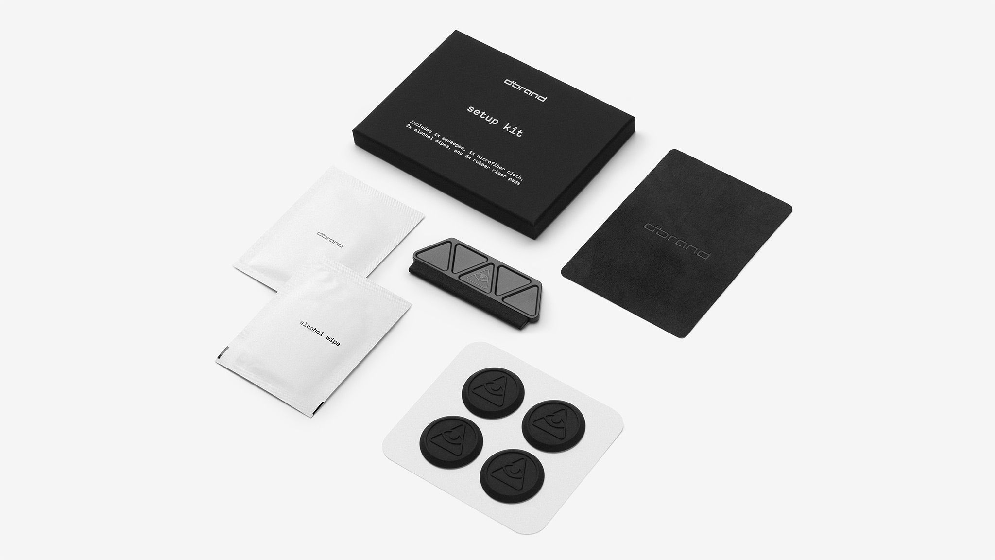 Everything included in the setup kit that you'll receive, laid out against a white background - two alcohol wipes, a squeegee, a microfiber cloth, and four rubber riser pads to aid in the installation process.