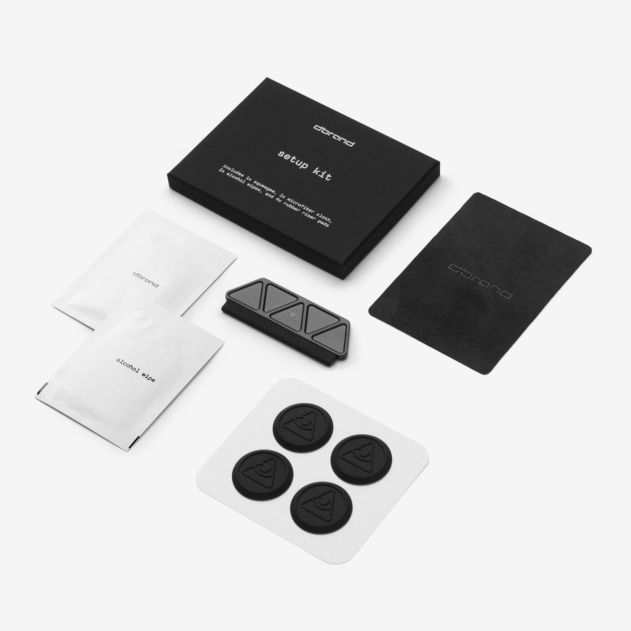Everything included in the setup kit that you'll receive, laid out against a white background - two alcohol wipes, a squeegee, a microfiber cloth, and four rubber riser pads to aid in the installation process.