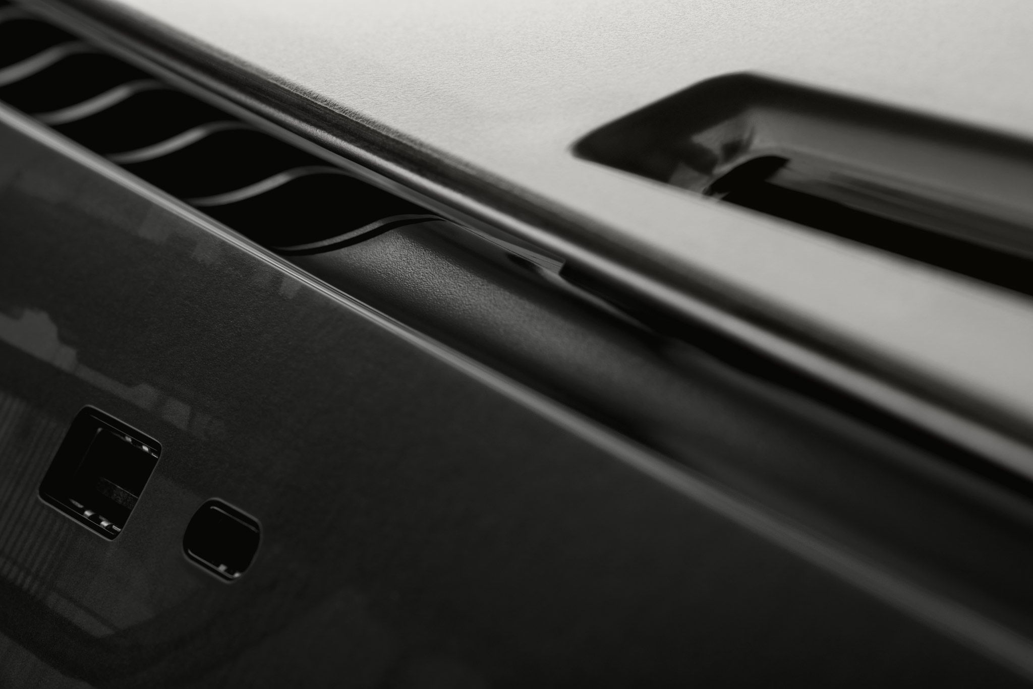 A close-up of the front panel of a PlayStation 5, with our Smoke Black Skin applied and visible around the ports of the console.