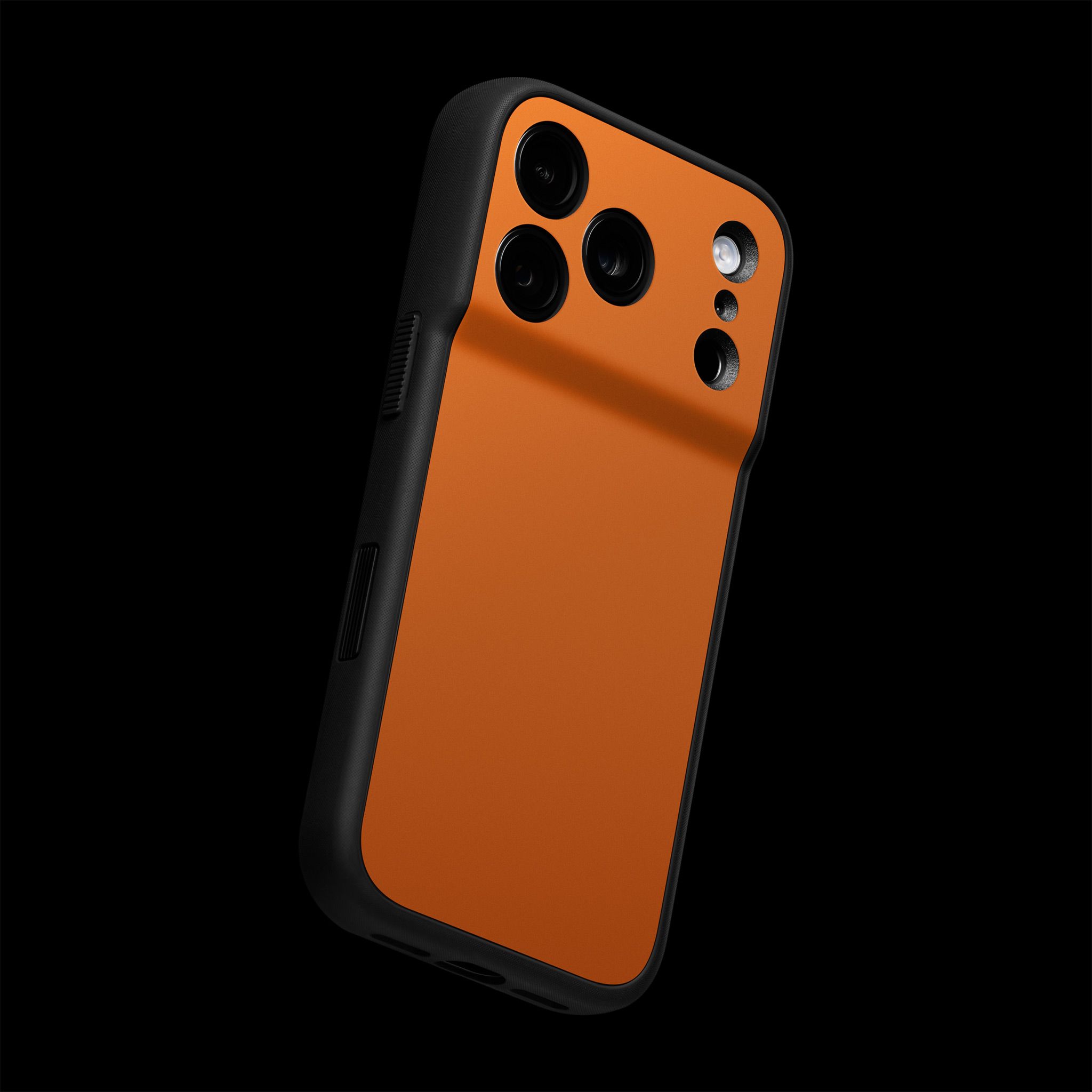 The back of an iPhone 17 Pro Max seen at a distance, with our Grip Case applied to it. The backplate of the Grip Case has a Cosmic Orange Grip Skin applied to it.