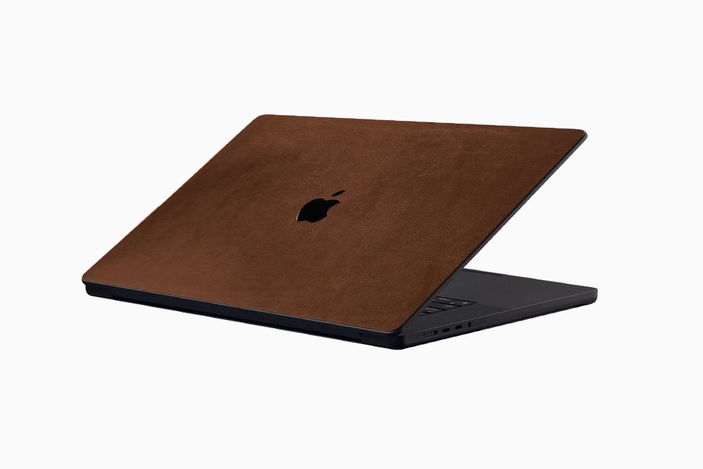 A MacBook with a dbrand Brown Leather skin applied to the top lid.