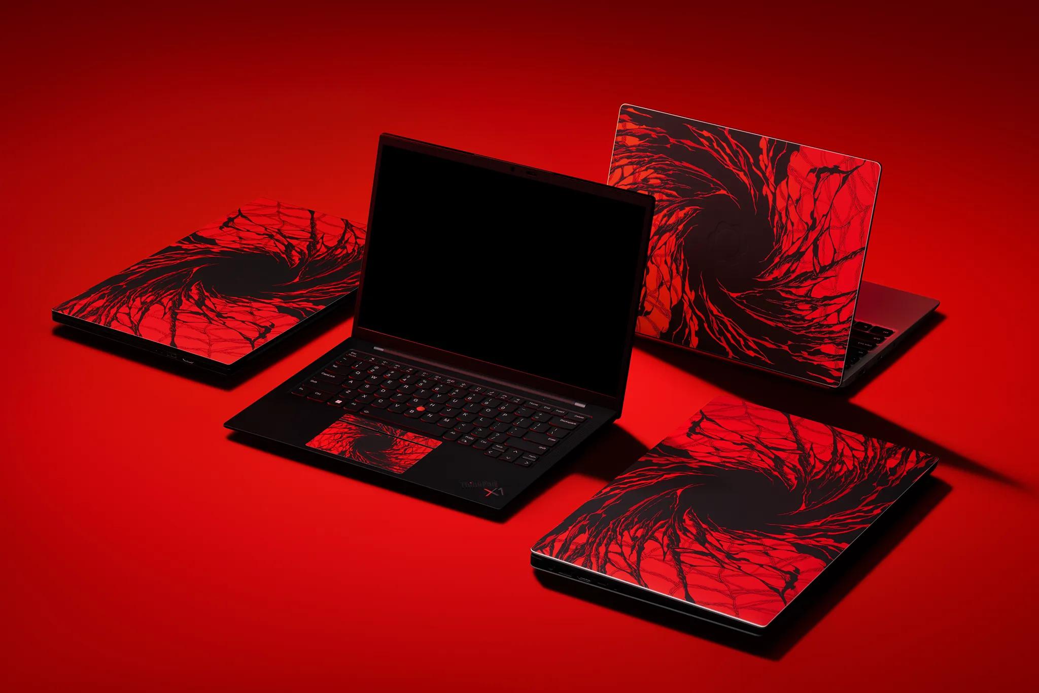 A variety of laptops against a red backdrop. Two on the sides are closed while two are open - one laptop faces the viewer with a black screen, while the other faces away. All of the devices are skinned in our Carnage material. 