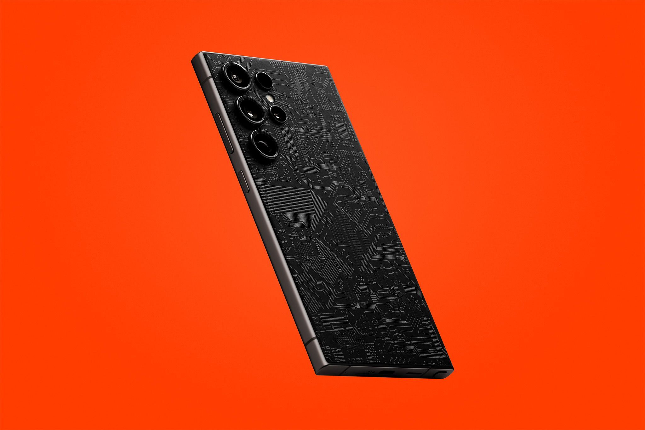An S24 Ultra seen from the back. The device has our Dark Circuit Skin on it, showing the black tone of the material with an orange backdrop.